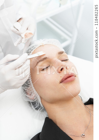 The young female client of cosmetic salon having a cleansing facial mask 118482265