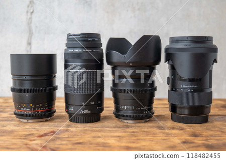 Four different camera lenses standing on a wooden surface 118482455