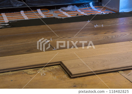 Renovation works. Close-up of installation of parquet and ceramic tile floor and heating cables for warm floor. 118482825