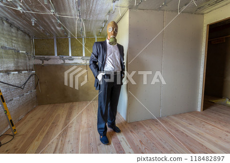 Strange man in businessman suit and gas protection mask inside a room under renovation works. 118482897