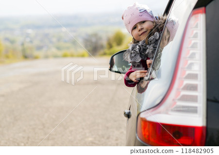 Pretty little girl in the car looking through car window. Travel concept. 118482905