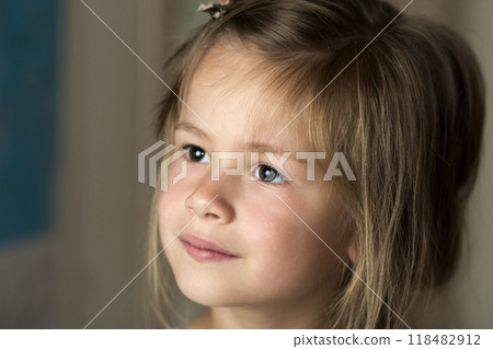 Portrait of little pretty young child girl with gray eyes and clip in scattered fine blond hair looking dreamily in distance on blurred sunny background. Beauty, dreams and innocence of childhood. 118482912