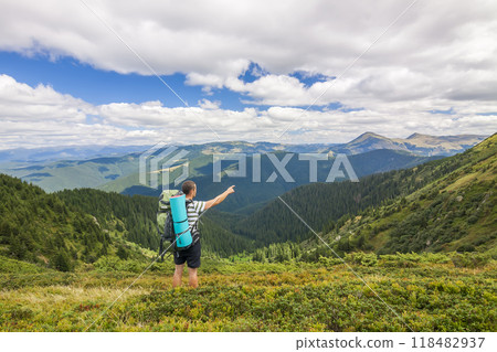 Hiker with a backpack standing in mountains 118482937