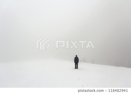 Far away lonely figure of a man standing outdoors in winter Far away lonely figure of a man standing outdoors in winter 118482941