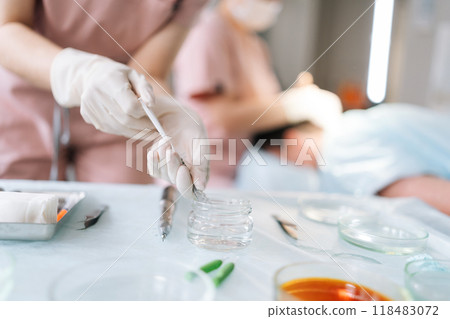 Closeup cropped shot of unrecognizable female doctor in gloves fill in syringe with medicine from glass bottle. Close-up hands of nurse holding syringe with liquid vaccines working in modern hospital. Closeup cropped shot of unrecognizable female doctor in gloves fill in syringe with medicine from glass bottle. Close-up hands of nurse holding syringe with liquid vaccines working in modern hospital. 118483072