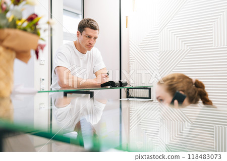 Male customer waiting for paying using credit card to pay on contactless NFC terminal at clinic counter. Handsome man making contactless payment with card at machine terminal at hotel reception. 118483073