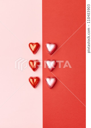 Two lines of heart shaped chocolate candies on pink and red background. Valentines Day concept 118483903