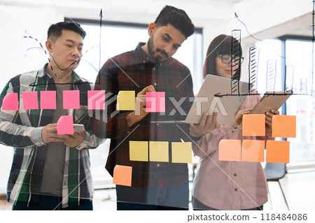 Team brainstorming with sticky notes and tablets in office 118484086