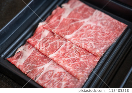 A close-up shot of sliced raw meat, arranged on a plate, ready to be cooked in a hot pot A close-up shot of sliced raw meat, arranged on a plate, ready to be cooked in a hot pot 118485218