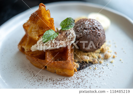 Waffle with chocolate ice cream served with cookie crumble, whipped cream and banana on plate 118485219