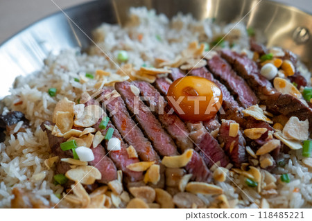 Beef with garlic fried rice, a dish of rice topped with rare beef served with pickled egg yolk with fish sauce on a pan 118485221
