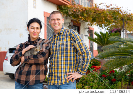 Man and woman with cats in their arms on the background of a country house 118486224
