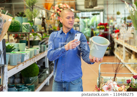 Man photographing flower pot in store 118486275
