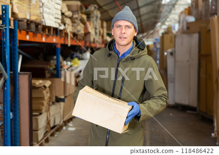 Warehouse worker carrying large box of goods in arehouse 118486422