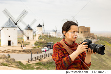 Tourist with camera in front of the windmills in Spanish city of Consuegra Tourist with camera in front of the windmills in Spanish city of Consuegra 118486428