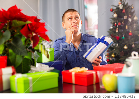 Man sitting at the table with X-mas presents Man sitting at the table with X-mas presents 118486432