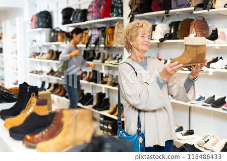 Mature european woman chooses winter boots Mature european woman chooses winter boots 118486433