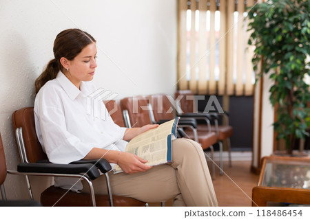 Woman sits on chair while waiting for reception in company office Woman sits on chair while waiting for reception in company office 118486454