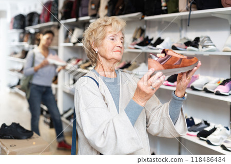 Mature european woman chooses sports sneakers 118486484