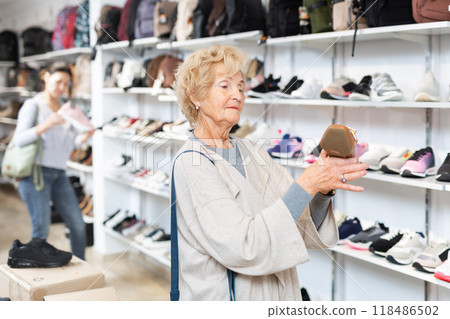 Granny choosing new shoes while standing in salesroom of shoeshop. 118486502