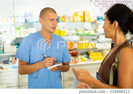 Male doctor writing recipe for client in drugstore 118486511