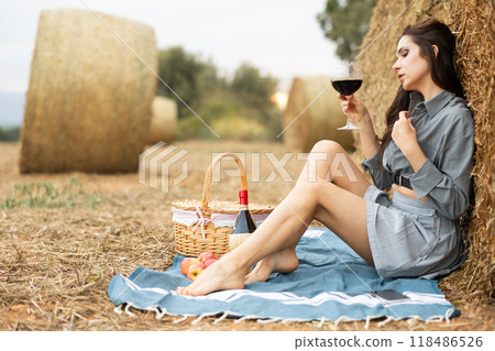 Woman sitting in shirt with wine during picnic Woman sitting in shirt with wine during picnic 118486526