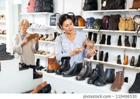 Woman selecting new shoes in shoeshop Woman selecting new shoes in shoeshop 118486530