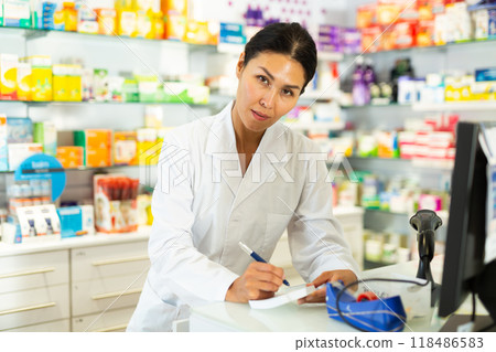 Female doctor standing at counter and writing 118486583