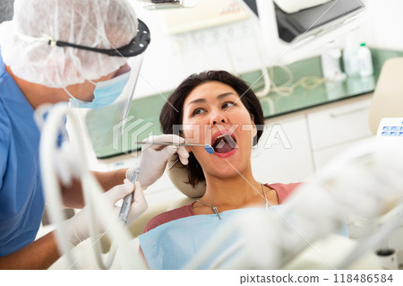 Dentist drilling tooth to asian female patient 118486584