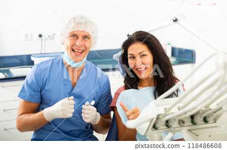 Portrait of a qualified smiling man dentist with a satisfied female patient Portrait of a qualified smiling man dentist with a satisfied female patient 118486608