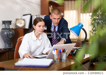 Man manager helping to woman during working at laptop Man manager helping to woman during working at laptop 118486621