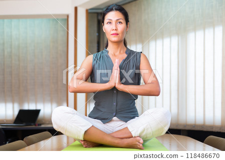 Businesswoman sitting at the table in lotus position Businesswoman sitting at the table in lotus position 118486670