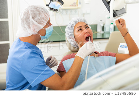 Dentist uses modern equipment and a computer to check patient teeth Dentist uses modern equipment and a computer to check patient teeth 118486680
