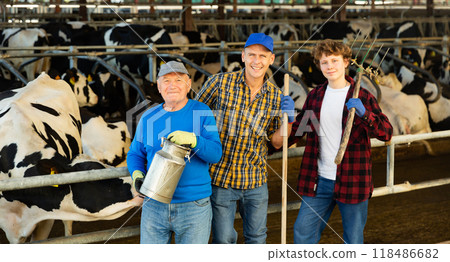 Various aged dairy farm workers in cowshed Various aged dairy farm workers in cowshed 118486682