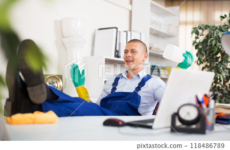 Relaxed cleaning service worker sitting in office with feet on table Relaxed cleaning service worker sitting in office with feet on table 118486789