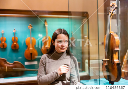 Woman viewing collections of ancient musical instruments in museum Woman viewing collections of ancient musical instruments in museum 118486867
