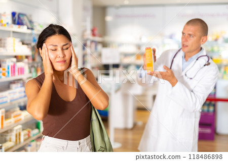 Oriental woman complaining about headache in chemist shop Oriental woman complaining about headache in chemist shop 118486898