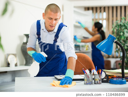 Man from cleaning service wiping office table 118486899