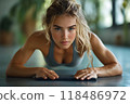 Focused and Determined Woman Doing Plank Core Strengthening Exercise on Fitness Mat in Wellness Studio Demonstrating Muscular Strength and Balance 118486972
