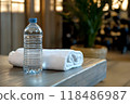 Water bottle and towel placed on a gym bench symbolizing the essential and items needed for a successful workout session or fitness routine 118486987