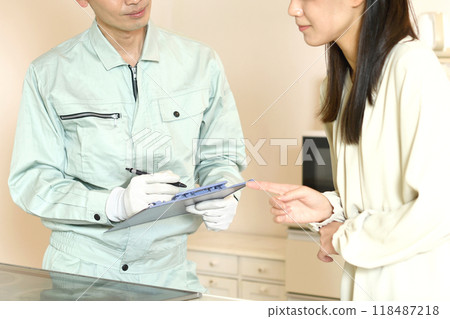 A male worker and a female customer having a conversation in front of an induction stove in a home kitchen A male worker and a female customer having a conversation in front of an induction stove in a home kitchen 118487218