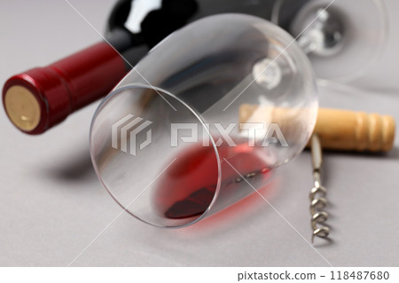 A bottle of wine, a glass and a corkscrew, on a gray background. 118487680