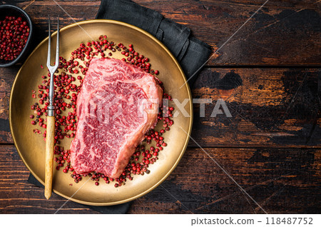 Raw Wagyu striploin, New york steak on a plate with pink peppper. Wooden background. Top view. Copy space 118487752