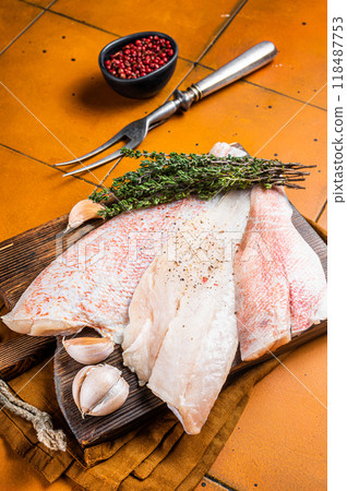Uncooked ocean red perch fillet, redfish with herbs and spices. Orange background. Top view 118487753