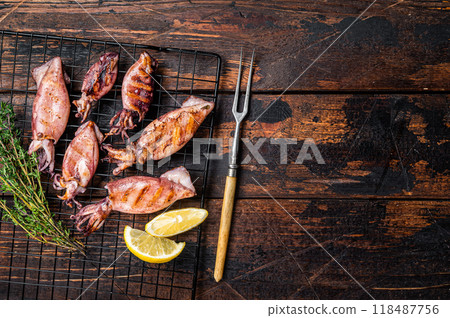 Bbq squid calamary on a rack. Black background. Top view. Copy space Bbq squid calamary on a rack. Black background. Top view. Copy space 118487756
