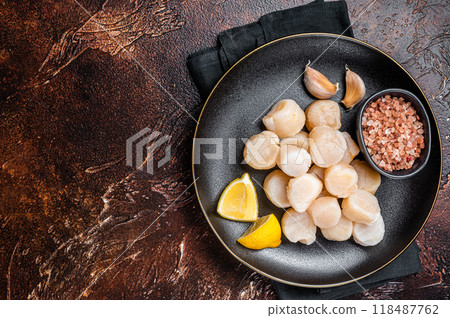 Raw sea scallops seafood on a plate with pink salt and lemon. Dark background. Top view. Copy space 118487762