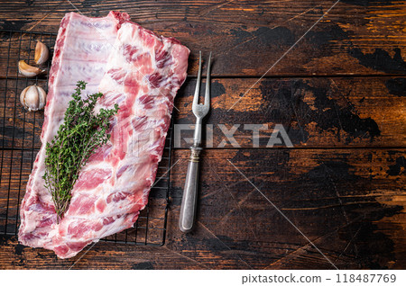 Raw pork spare ribs on a rack with herbs. Wooden background. Top view. Copy space 118487769