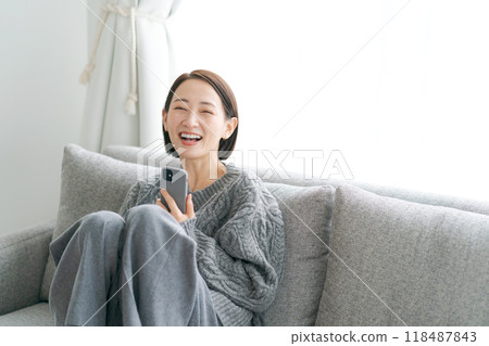 坐在沙發上使用智能手機的女人 118487843