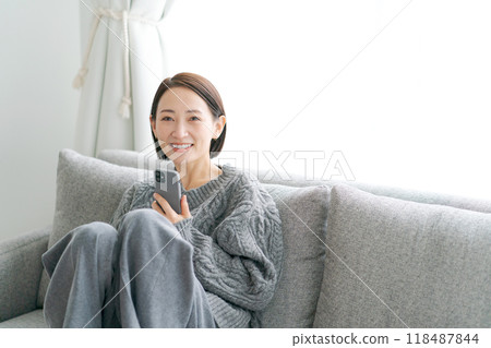 坐在沙發上使用智能手機的女人 118487844