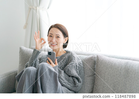 坐在沙發上使用智能手機的女人 坐在沙發上使用智能手機的女人 118487898